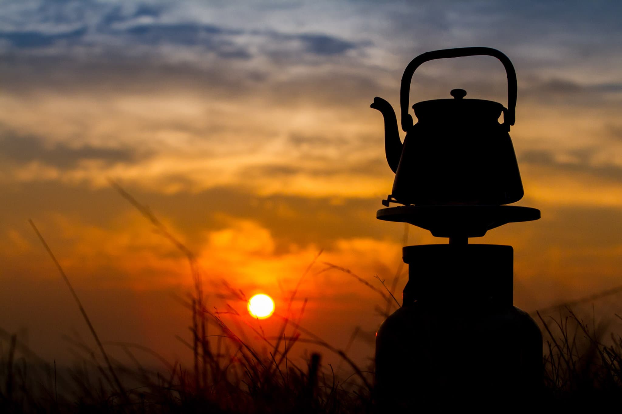 Wasserkessel auf einem Campingkocher im Sonnenuntergang