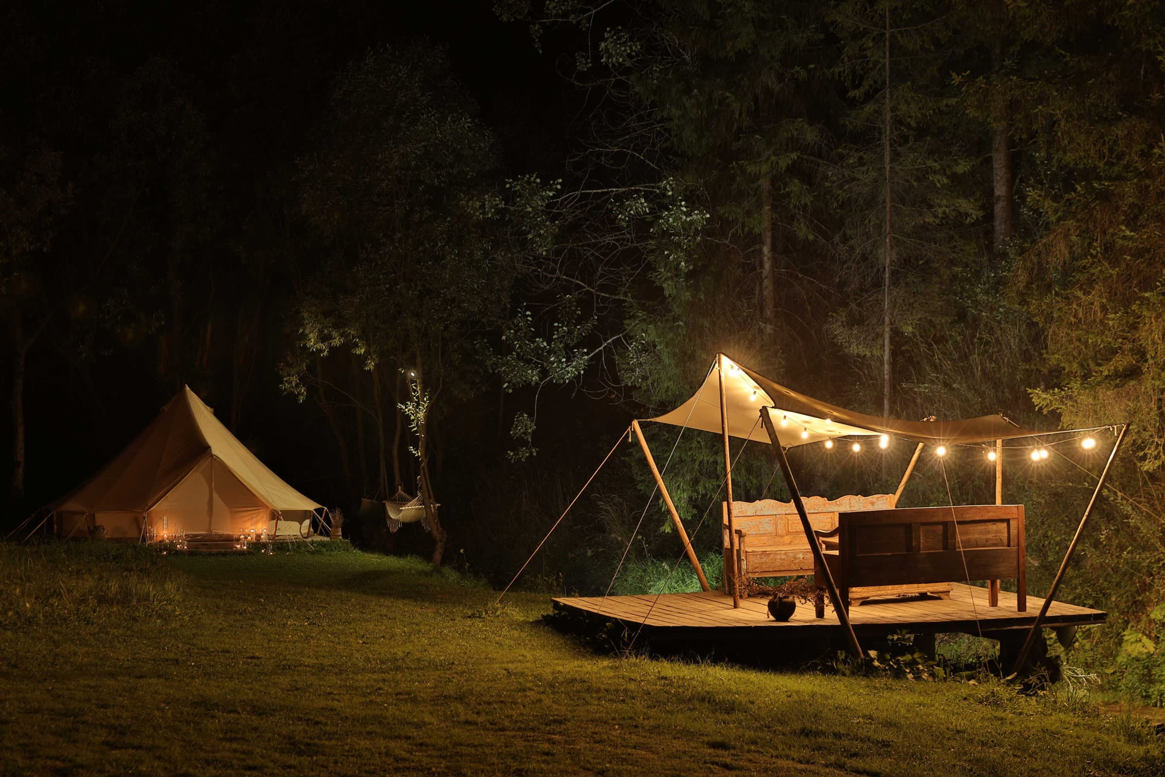 Glamping-Zelte und Lounge mit Lichterketten im Wald